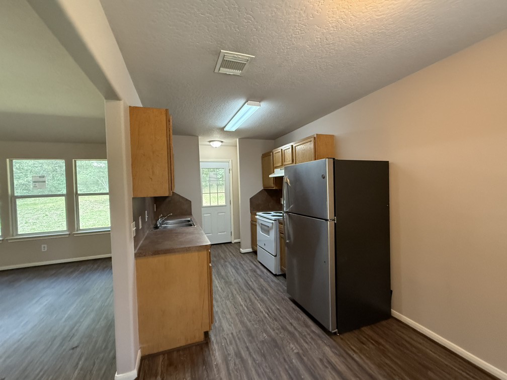 12595 Royal Springs Road Conroe, TX 77303 - Photo 12 of 26 a kitchen with a refrigerator a stove and wooden floor
