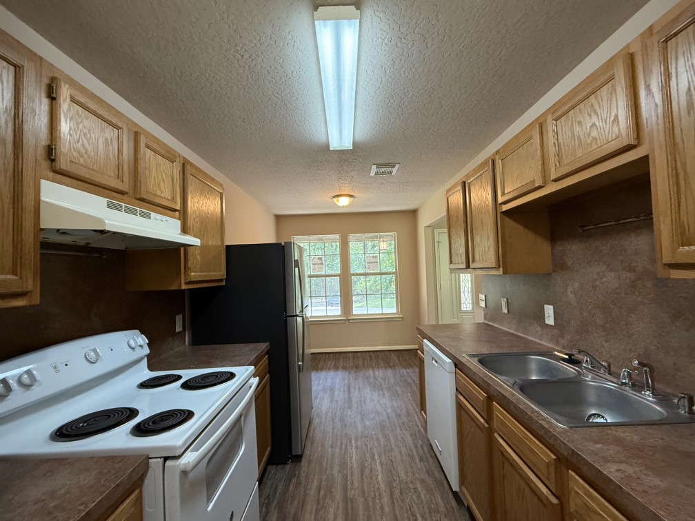 12595 Royal Springs Road Conroe, TX 77303 - Photo 6 of 26 a kitchen that has a sink a stove and a wooden floor