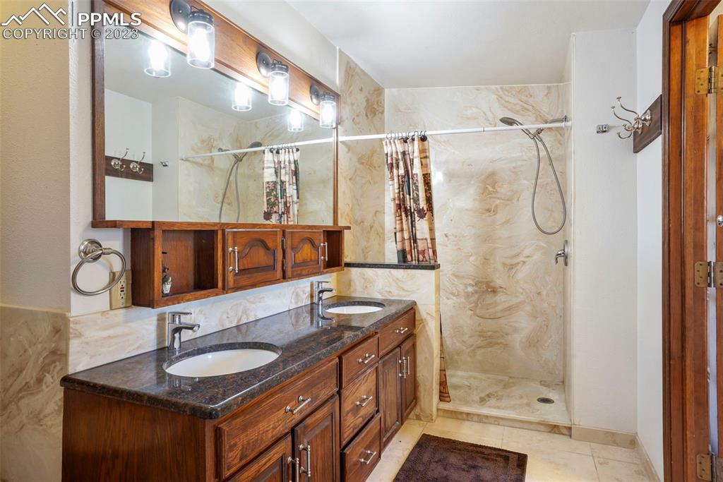 24725 Speer Road Calhan, CO 80808 - Photo 24 of 48 a bathroom with a granite countertop sink a mirror a shower and a mirror