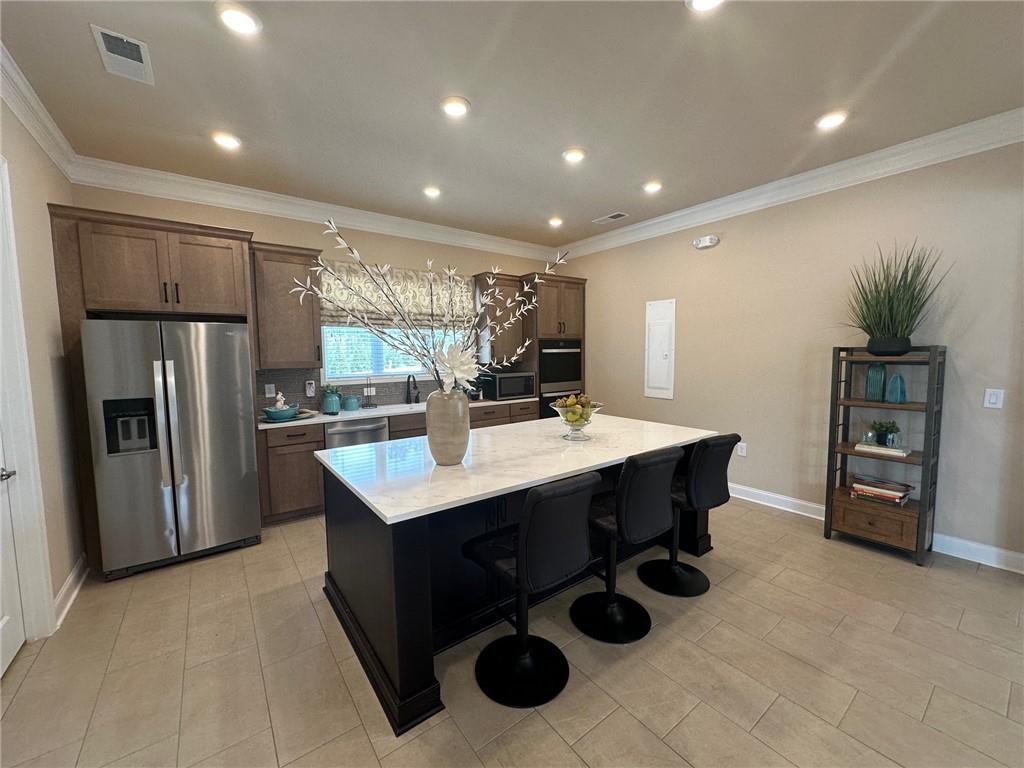 1001 Calypso Way, Unit 1001 Cumming, GA 30040 - Photo 24 of 27 a kitchen with stainless steel appliances kitchen island granite countertop a sink a counter and chairs