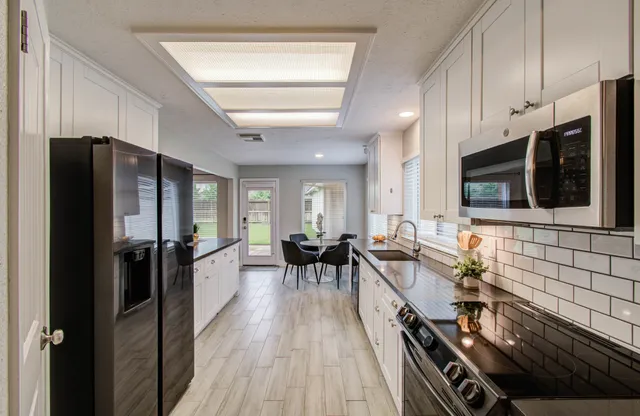 a kitchen with stainless steel appliances granite countertop a refrigerator and a stove top oven