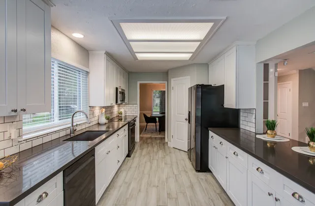 a large kitchen with granite countertop a large counter top sink and stainless steel appliances