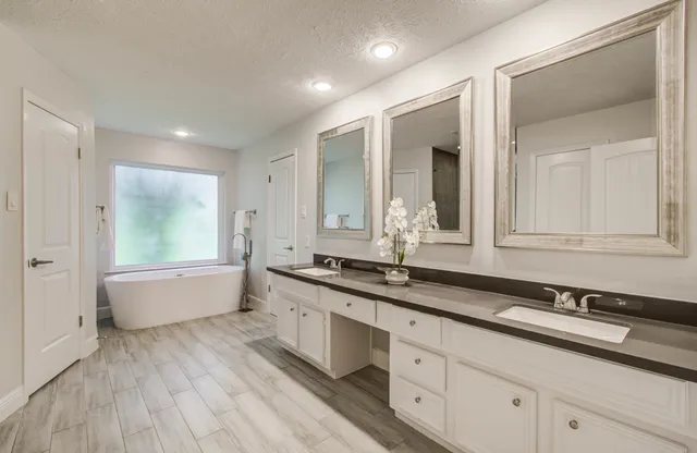 a bathroom with a granite countertop sink mirror and bathtub