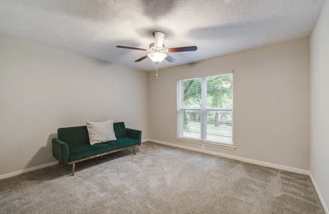 an empty room with windows and ceiling fan