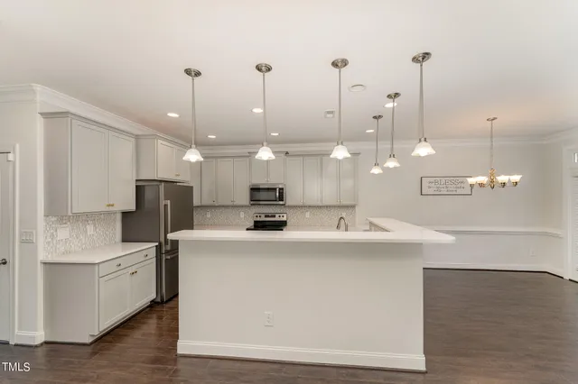 a view of a kitchen with kitchen island a sink stainless steel appliances and a chandelier