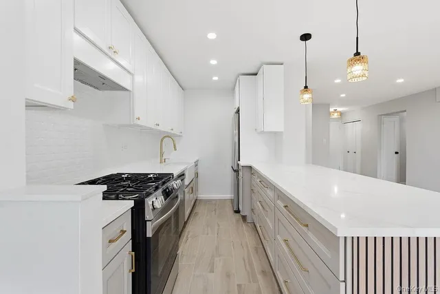 a kitchen with stainless steel appliances a stove a sink a refrigerator and a wooden floor