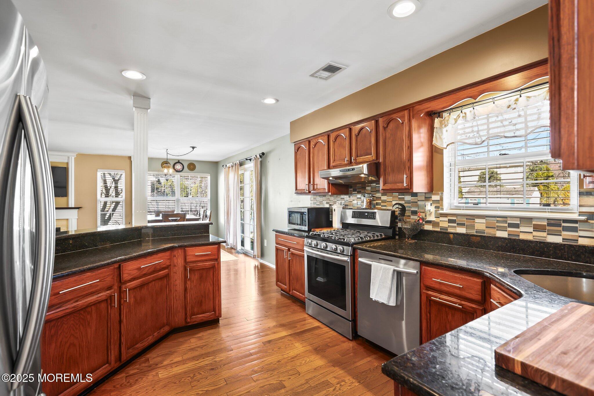 21 Sun Hollow Road Howell, NJ 07731 - Photo 14 of 47 a kitchen with stainless steel appliances granite countertop wooden cabinets a sink dishwasher a stove and a refrigerator with wooden floor