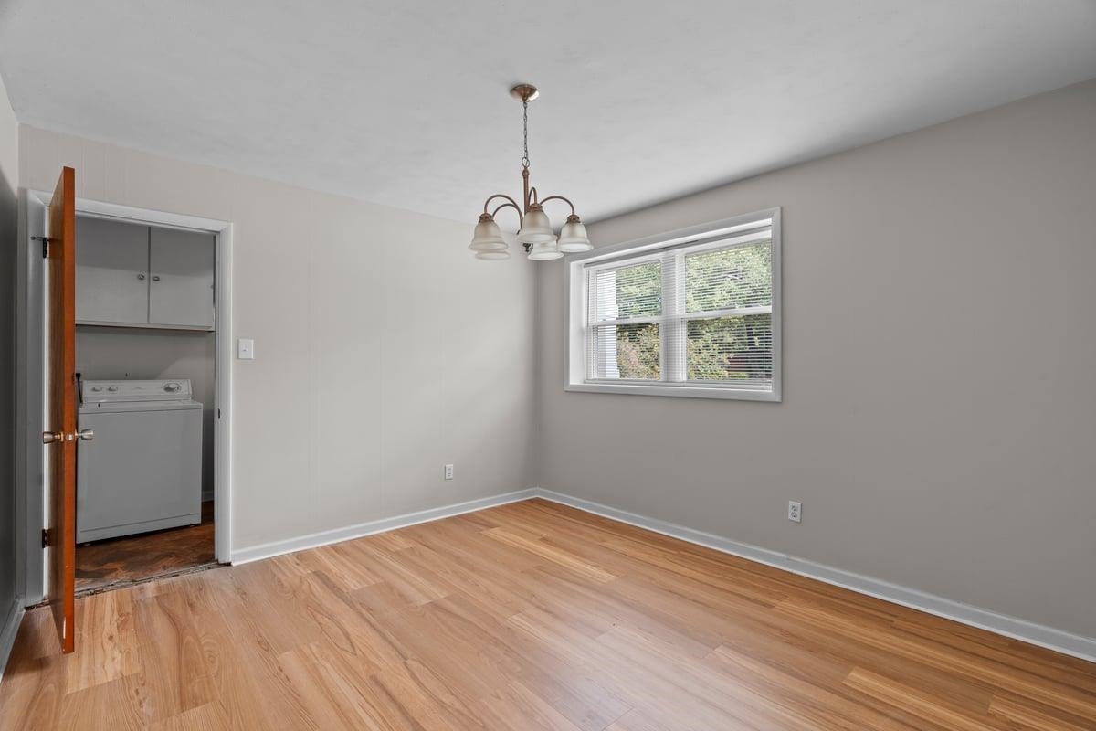 3221 East Raines Road Memphis, TN 38118 - Photo 4 of 28 Unfurnished dining area with washer / clothes dryer, light wood-style floors, and a chandelier