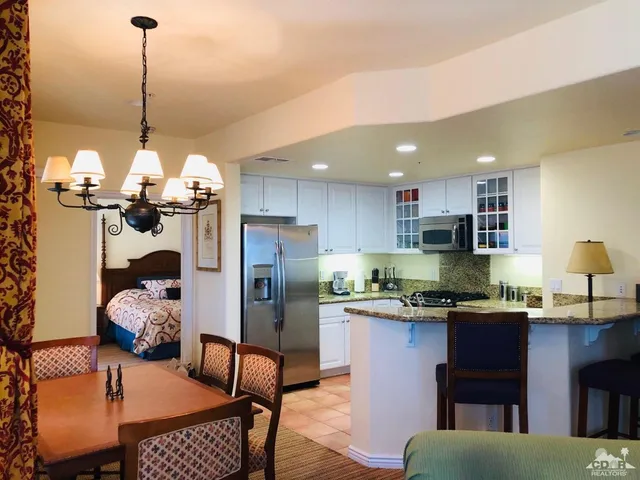 a kitchen with stainless steel appliances granite countertop a refrigerator a sink dishwasher a dining table and chairs with wooden floor