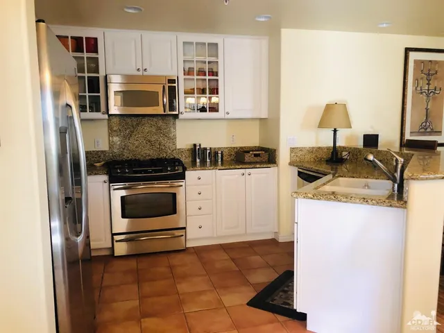 a kitchen with granite countertop a stove top oven microwave and cabinets