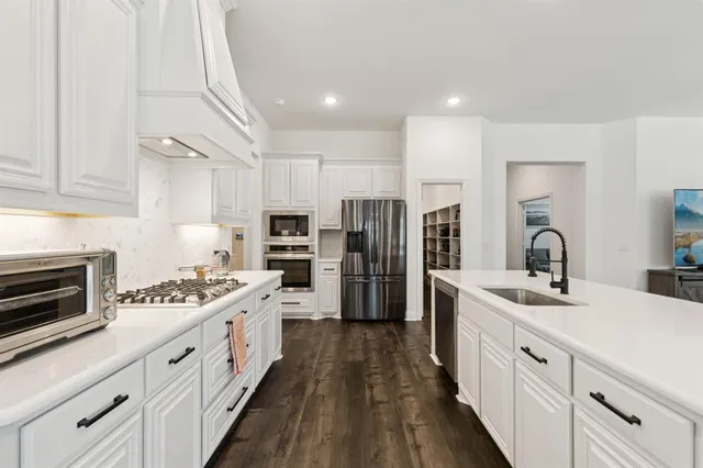 a kitchen with stainless steel appliances kitchen island granite countertop a sink stove refrigerator and cabinets