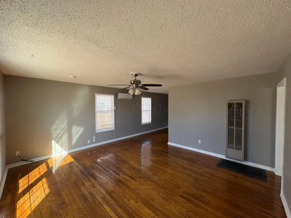 a view of an empty room with window and wooden floor