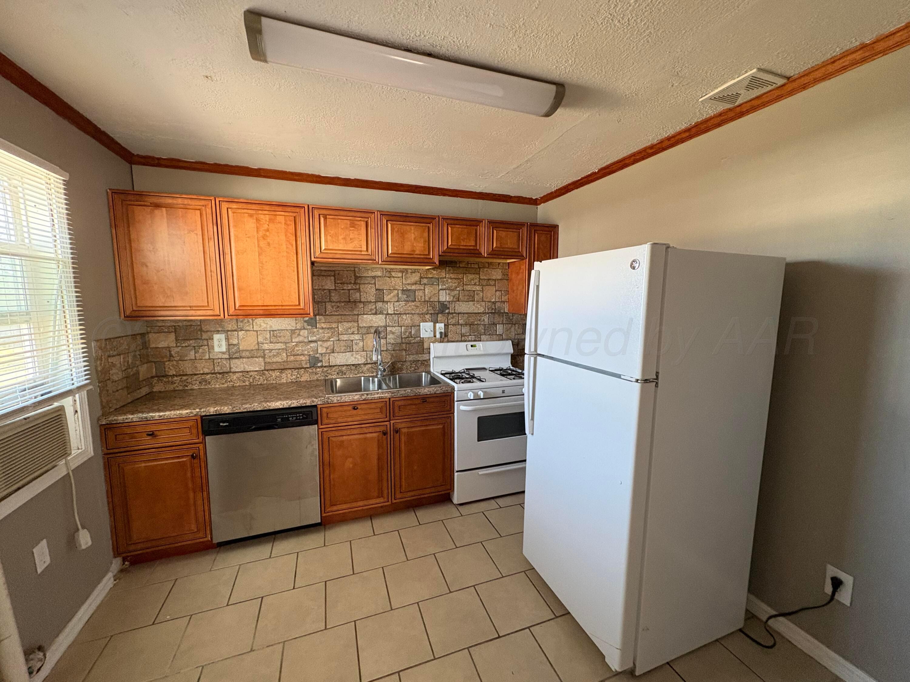 4119 Parker Street Amarillo, TX 79110 - Photo 4 of 8 a kitchen with stainless steel appliances granite countertop a refrigerator and a sink