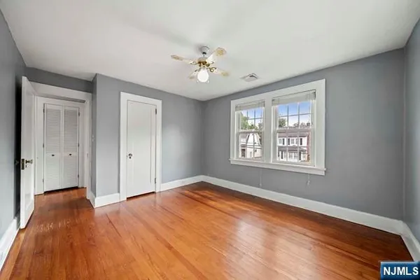 a view of empty room with wooden floor and fan