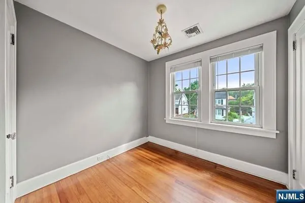 a view of empty room with window and wooden floor