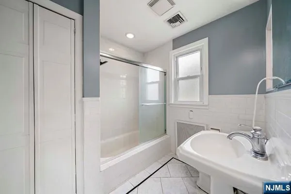 a bathroom with a bathtub shower sink and mirror
