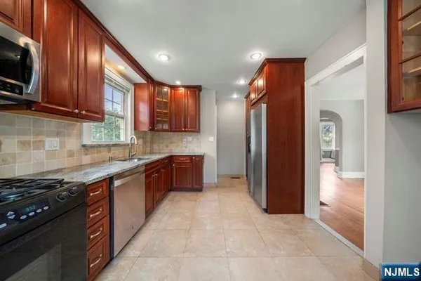 a large kitchen with stainless steel appliances granite countertop a stove refrigerator and cabinets