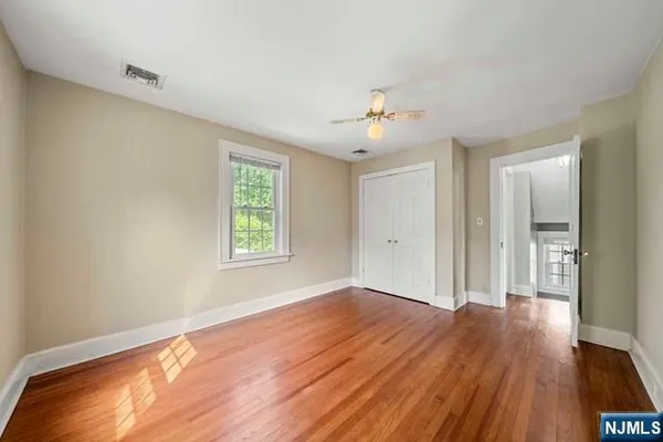 a view of an empty room with window and wooden floor