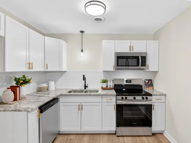 a kitchen with stainless steel appliances granite countertop a sink a stove a microwave and cabinets