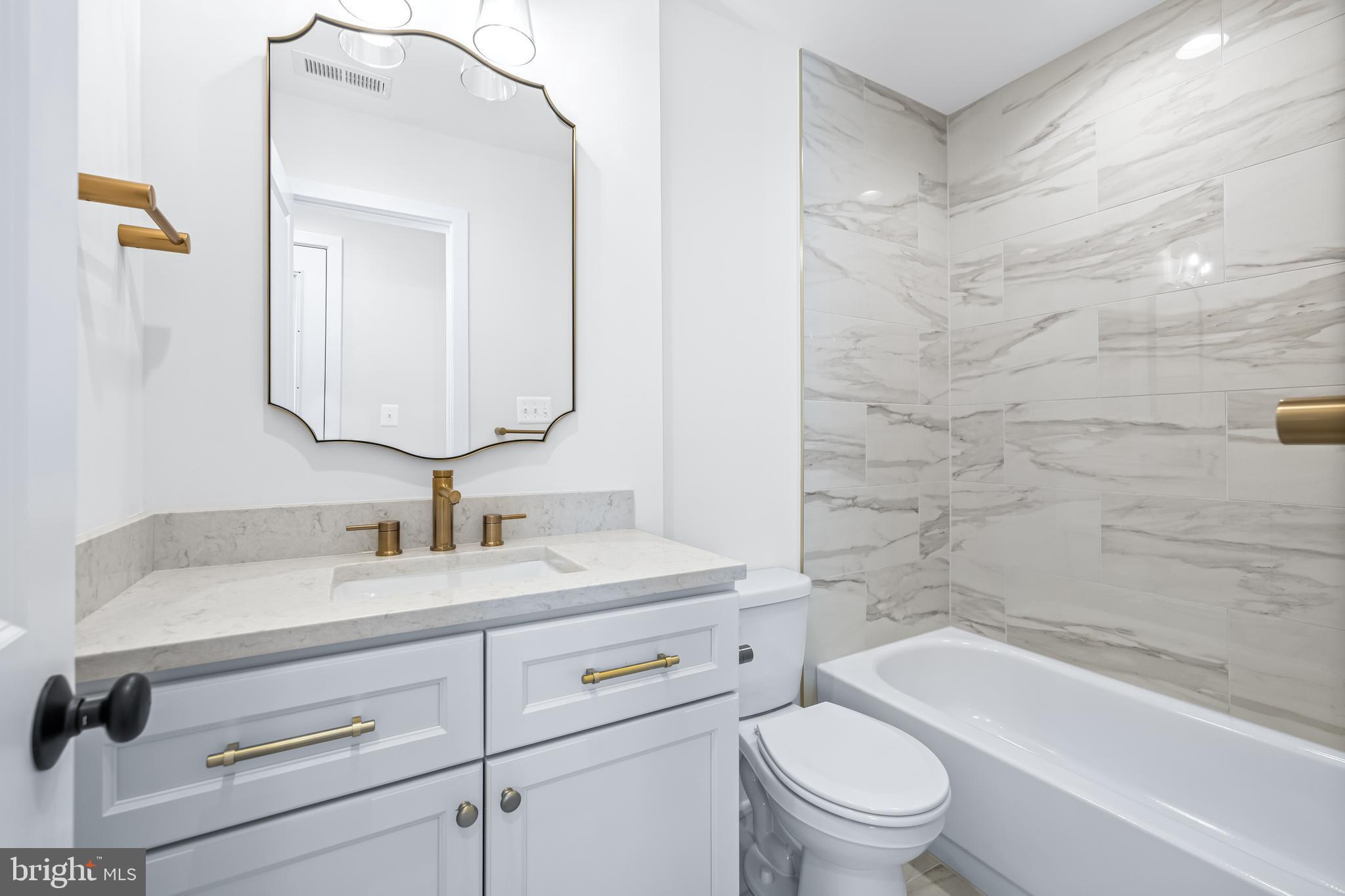 1317 Webster Street Baltimore, MD 21230 - Photo 19 of 32 a bathroom with a toilet a sink a vanity a mirror and bathtub