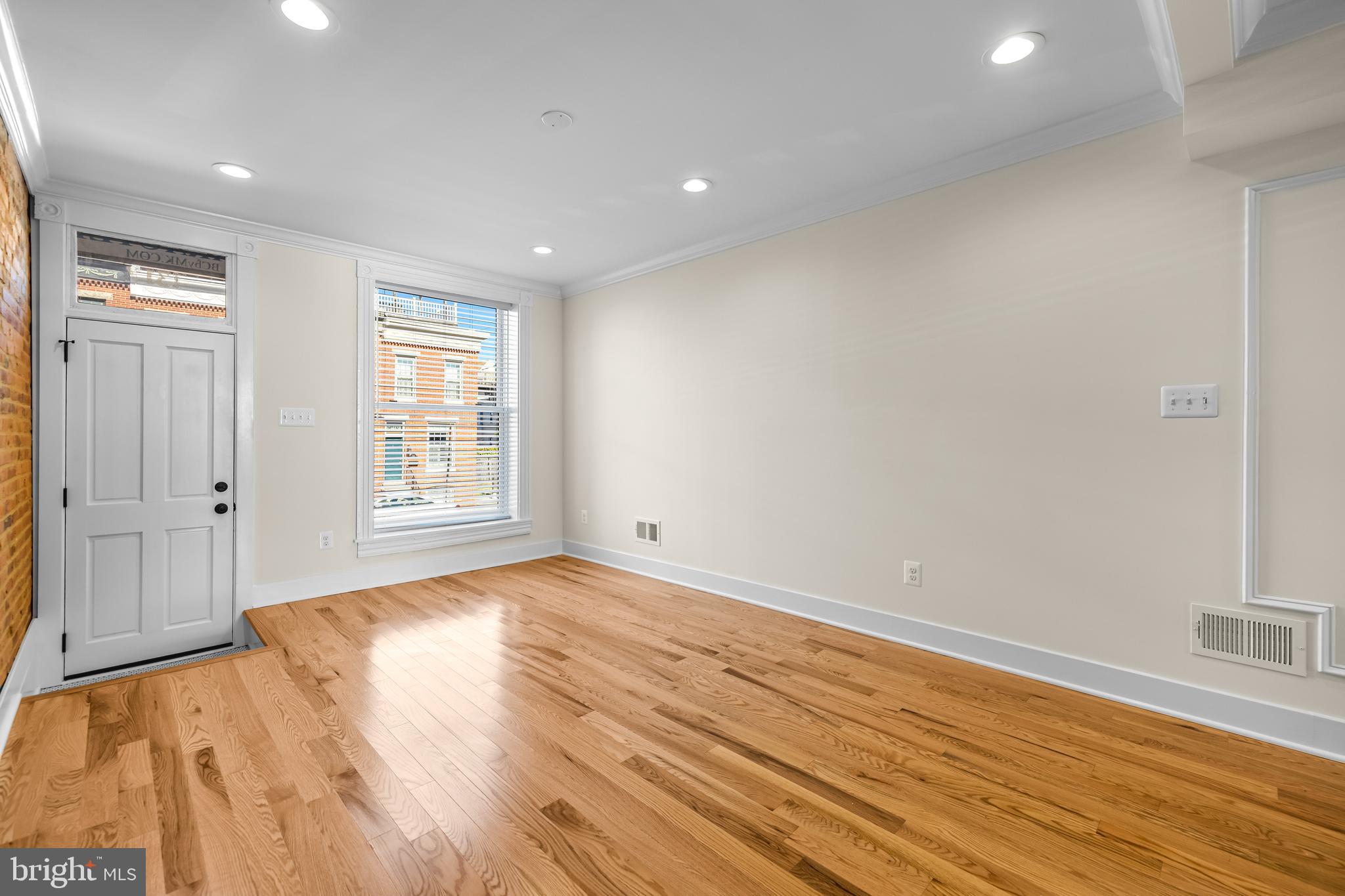 1317 Webster Street Baltimore, MD 21230 - Photo 6 of 32 an empty room with wooden floor and windows