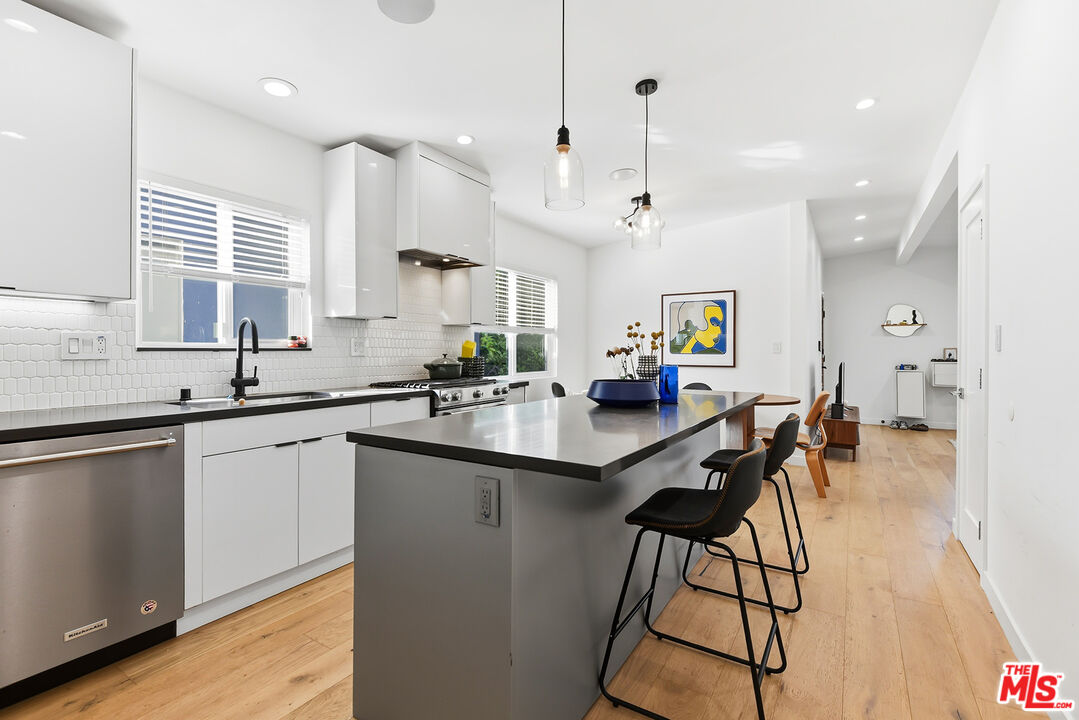 a kitchen with stainless steel appliances kitchen island a table chairs in it and wooden floors