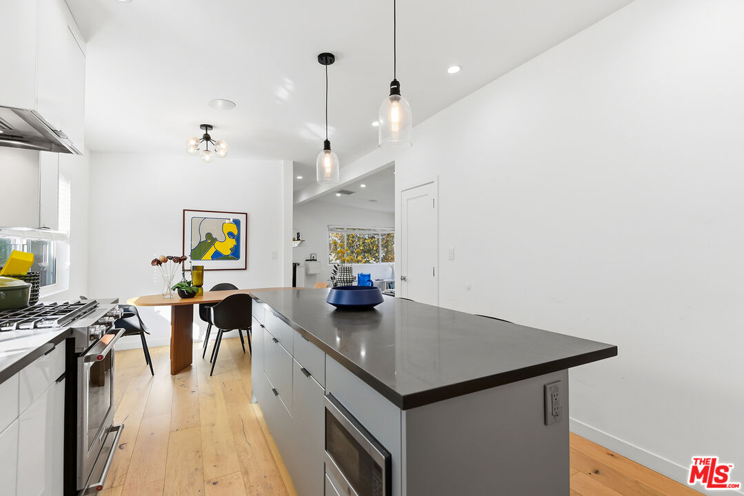 2603 Abbot Kinney Boulevard, Unit 1/2 Venice, CA 90291 - Photo 8 of 16 a kitchen with stainless steel appliances granite countertop a stove a refrigerator a sink a dining table and chairs with wooden floor