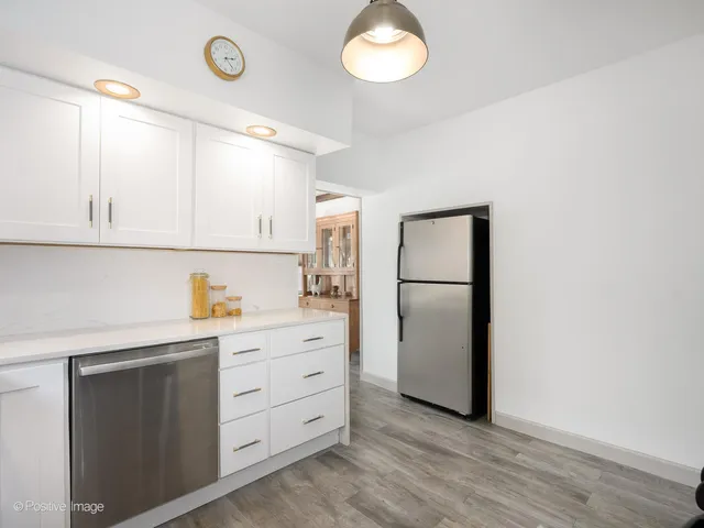 a kitchen with white cabinets and refrigerator