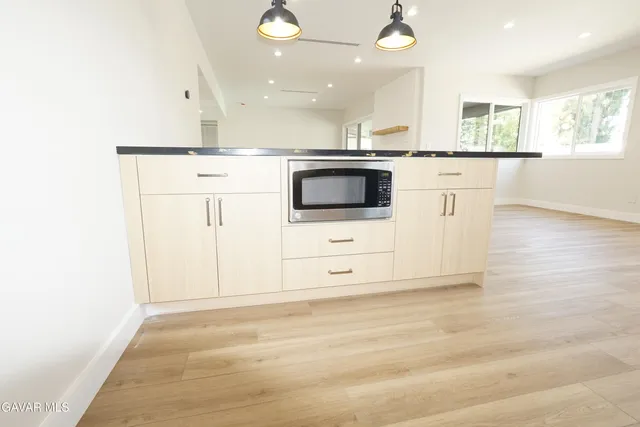 a large kitchen with stainless steel appliances granite countertop a sink and a stove top oven with wooden floor