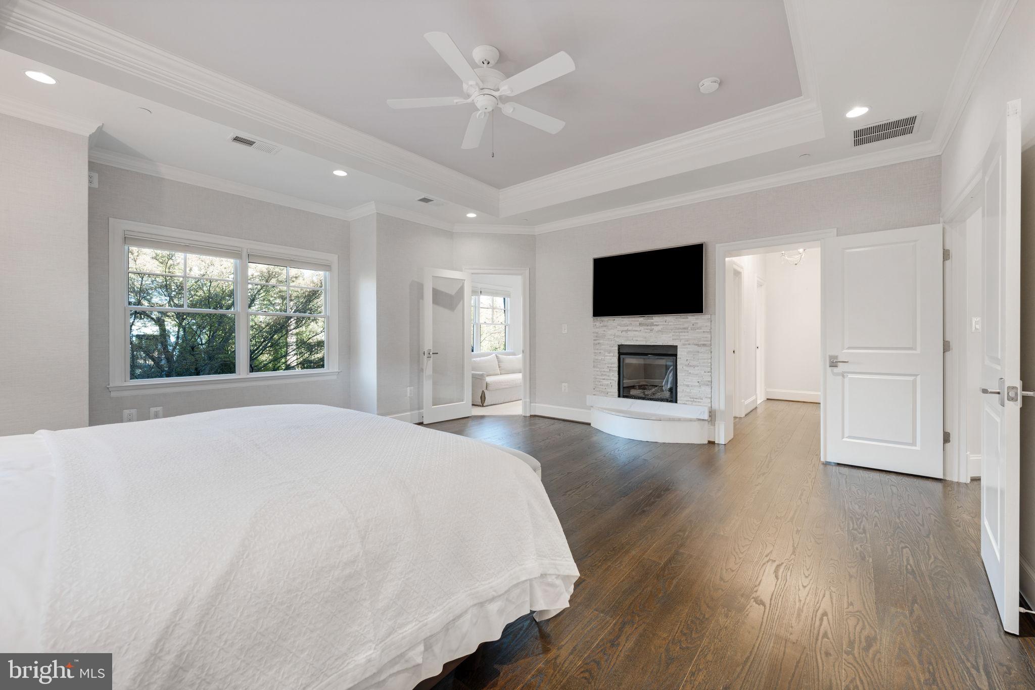 8505 Rayburn Road Bethesda, MD 20817 - Photo 23 of 49 a spacious bedroom with a large bed a flat tv screen and a fireplace