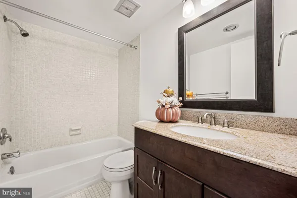 a bathroom with a granite countertop sink a mirror a toilet and a bathtub