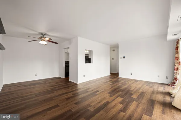 a view of a big room with wooden floor and chandelier fan