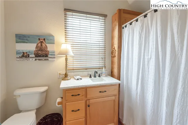 a bathroom with a toilet a sink a mirror and a window