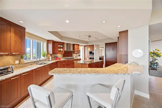 a large kitchen with granite countertop lots of white cabinets appliances and furniture