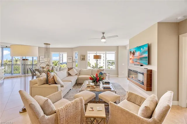 a living room with furniture a flat screen tv and a floor to ceiling window