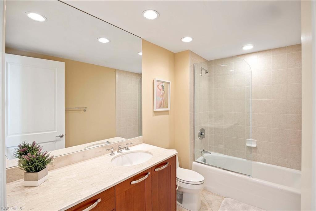 13675 Vanderbilt Drive, Unit 510 Naples, FL 34110 - Photo 28 of 37 a bathroom with a granite countertop sink a toilet and shower