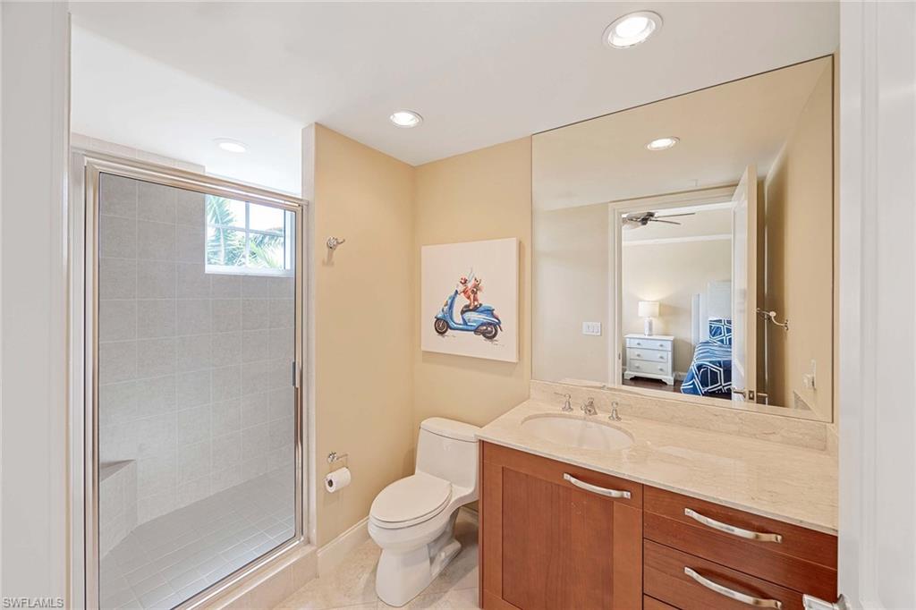 13675 Vanderbilt Drive, Unit 510 Naples, FL 34110 - Photo 30 of 37 a spacious bathroom with a toilet a sink a mirror and a shower