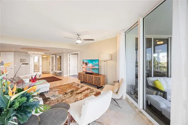 a living room with furniture a flat screen tv and a floor to ceiling window