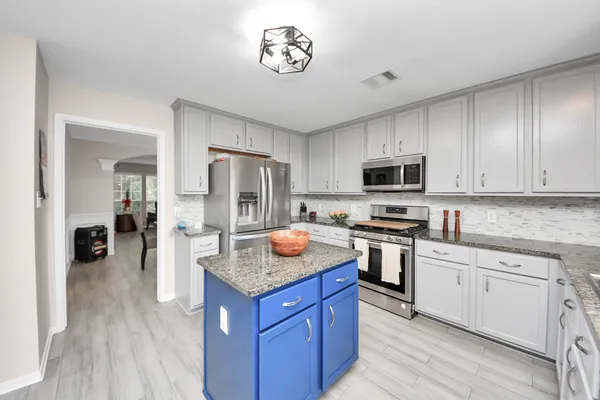 a kitchen with stainless steel appliances granite countertop a stove top oven a refrigerator a sink and dishwasher with wooden floor