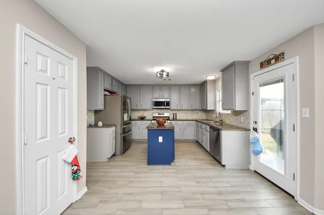 a kitchen with stainless steel appliances kitchen island granite countertop a refrigerator and cabinets