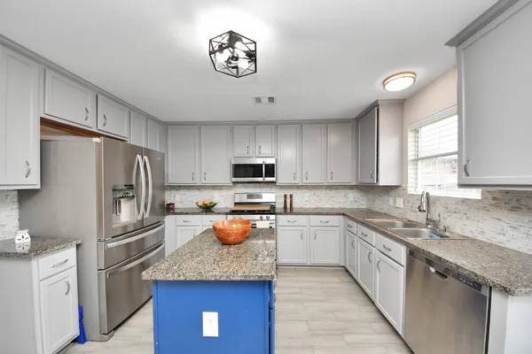 a kitchen with stainless steel appliances granite countertop a sink refrigerator stove and microwave
