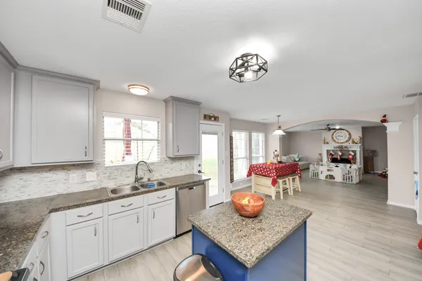 a kitchen with a refrigerator a sink dishwasher a dining table and chairs with wooden floor