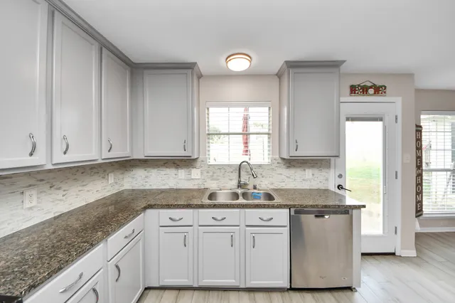 a kitchen with granite countertop a sink cabinets and window