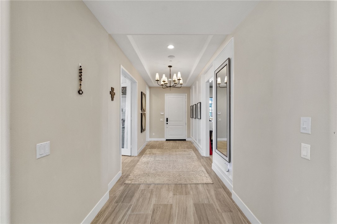 11463 Explorer Court Temescal Valley, CA 92883 - Photo 10 of 59 a view of a hallway with wooden floor and a chandelier