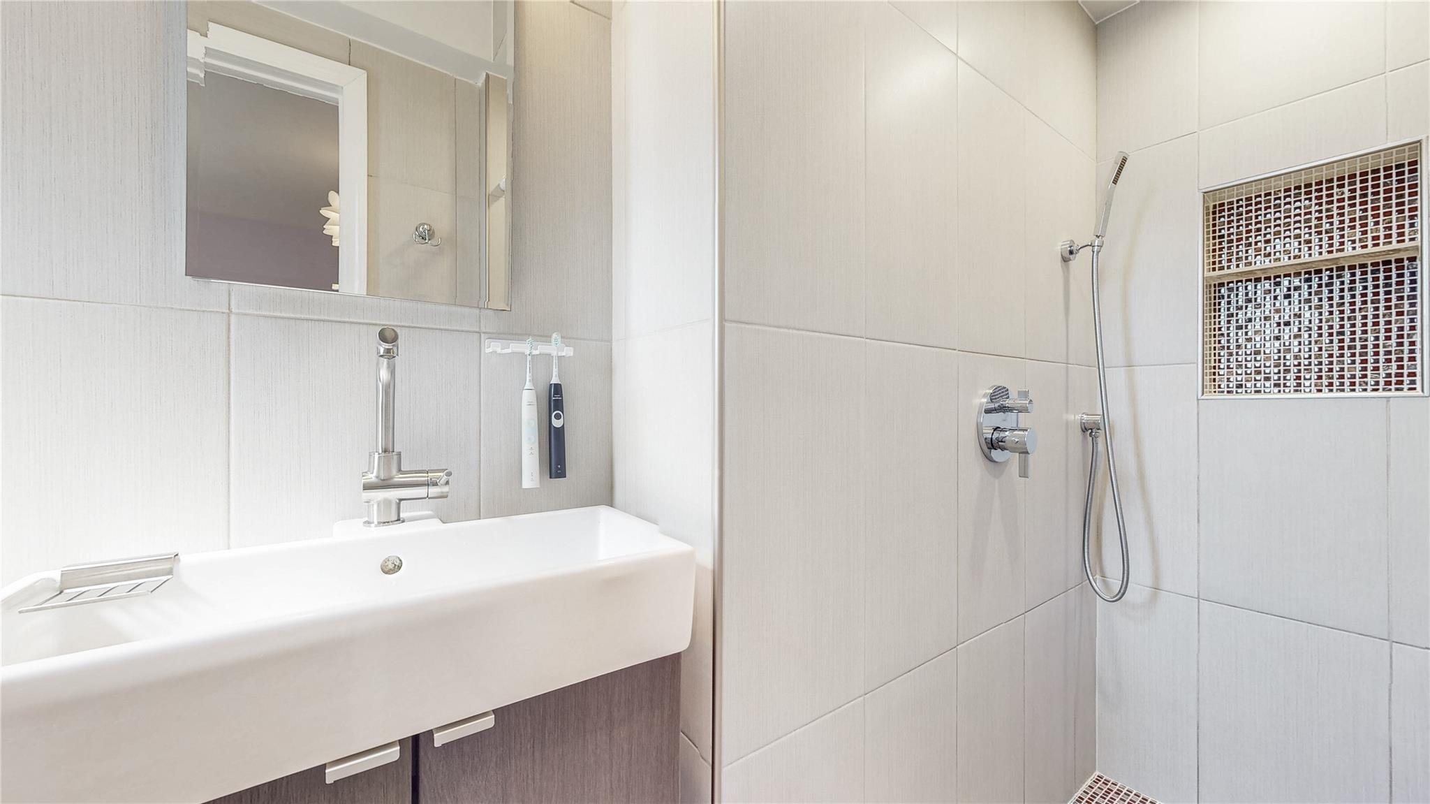 143-50 Hoover Avenue, Unit 507 Queens, NY 11435 - Photo 19 of 24 Bathroom featuring a sink, tile walls, and a tile shower