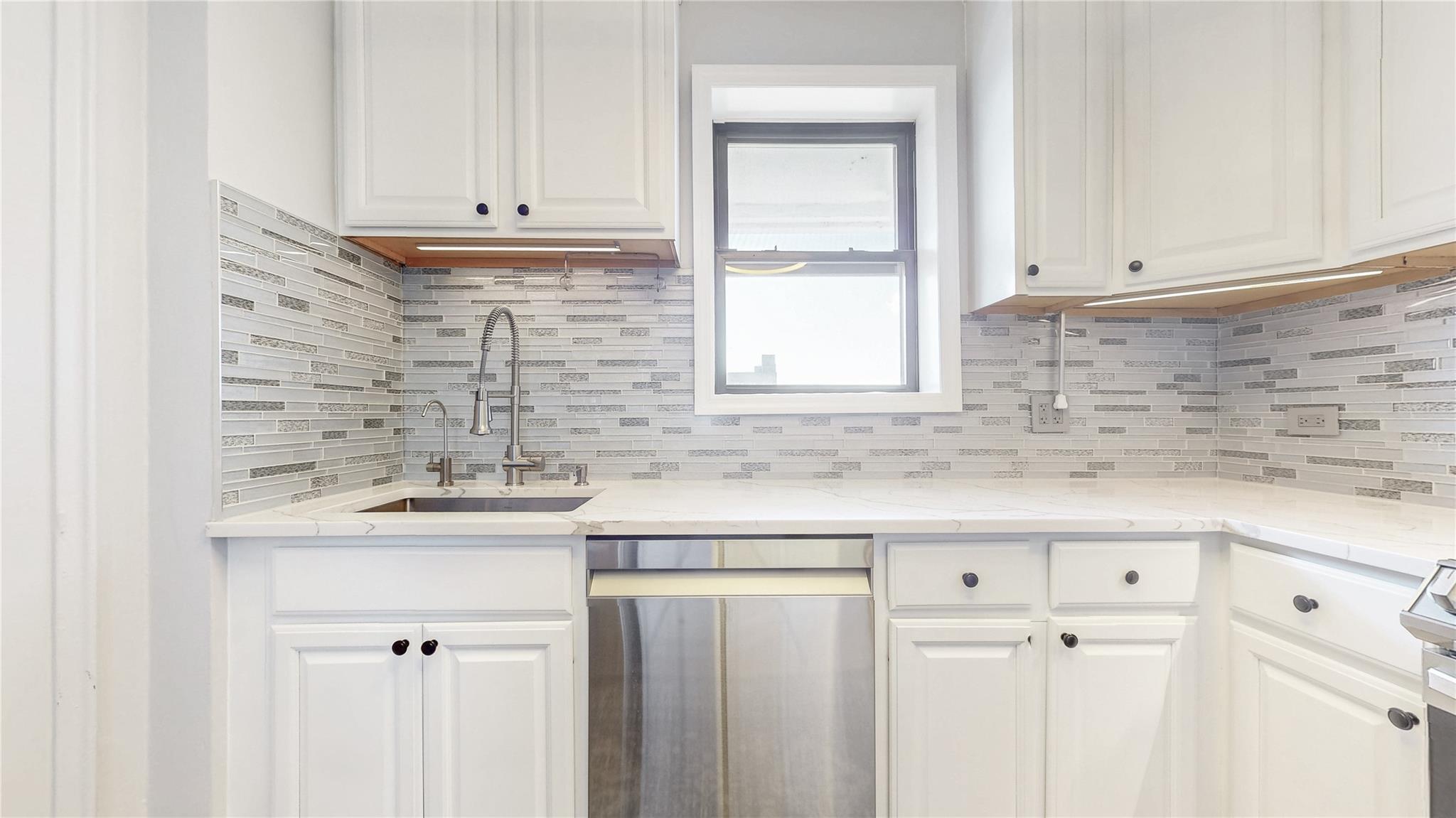 143-50 Hoover Avenue, Unit 507 Queens, NY 11435 - Photo 8 of 24 Kitchen with appliances with stainless steel finishes, white cabinets, decorative backsplash, and a sink