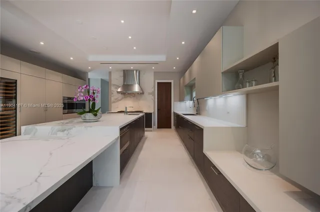 a large kitchen with stainless steel appliances kitchen island a large counter top a sink and a refrigerator