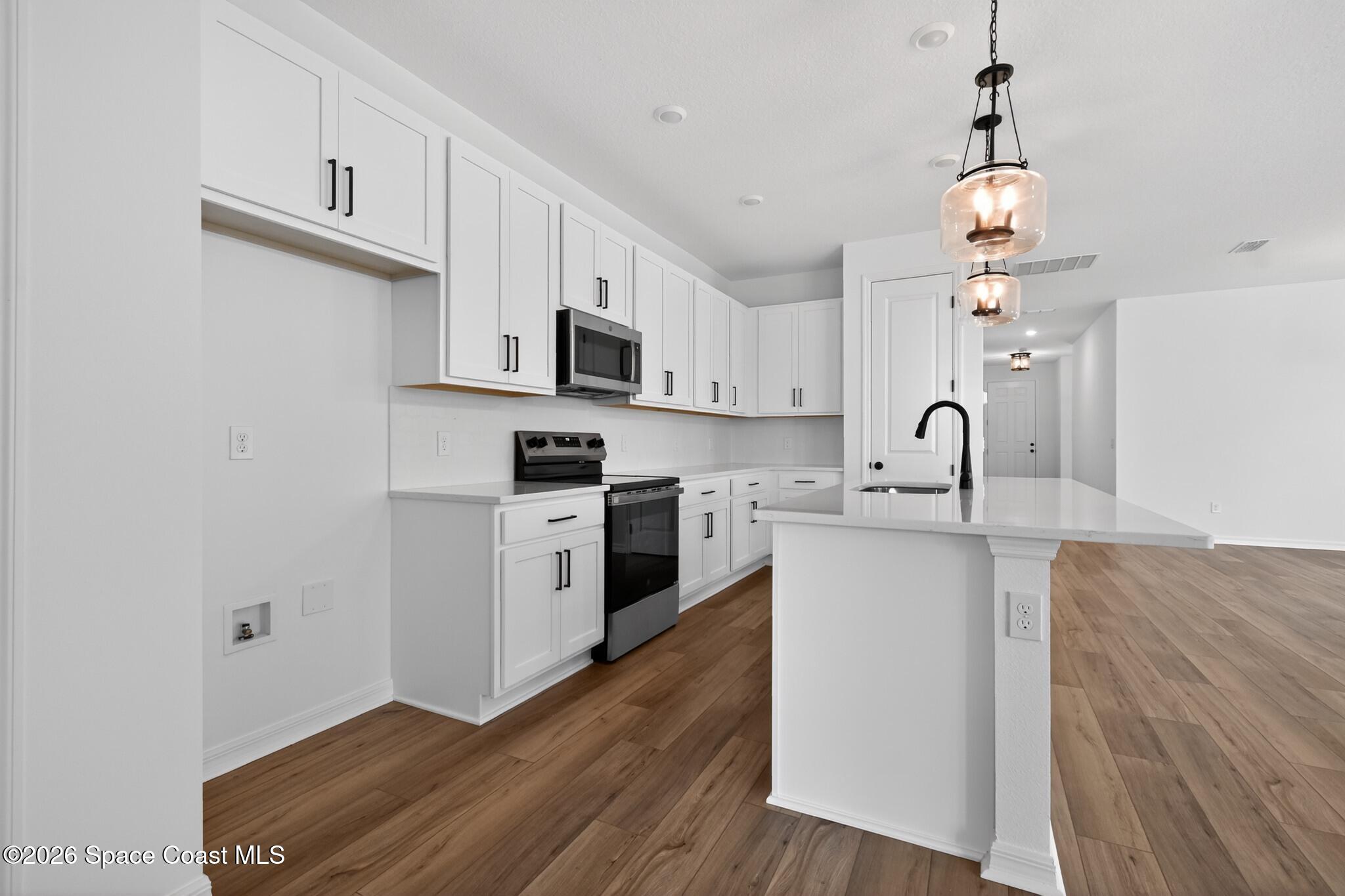 4372 Dockyard Drive Rockledge, FL 32955 - Photo 8 of 24 a kitchen with kitchen island a sink cabinets and wooden floor