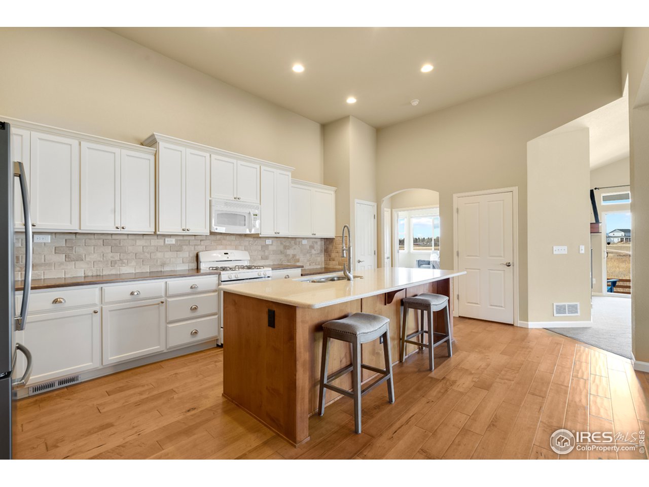 709 Snowy Plain Road Fort Collins, CO 80525 - Photo 4 of 40 Open kitchen with beautiful hardwood floors, center island with breakfast bar seating, stainless steel appliances, gas range and quartz counters.