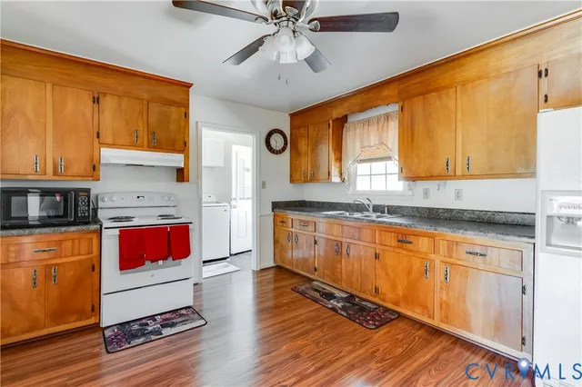 a kitchen with stainless steel appliances granite countertop a sink cabinets and wooden floor